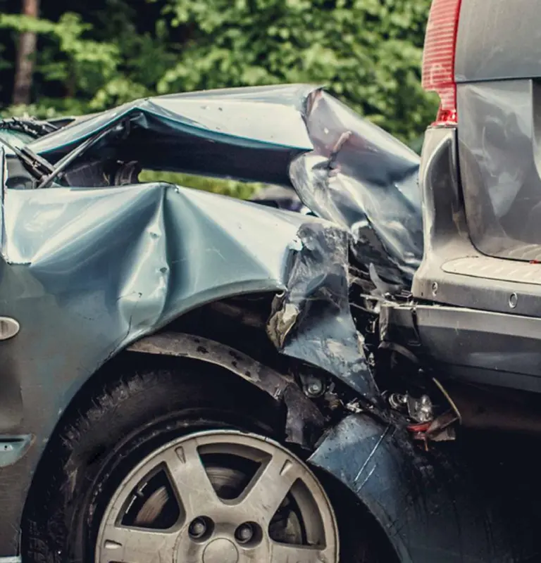 Close-up of two cars involved in a rear-end collision with significant front and rear damage.