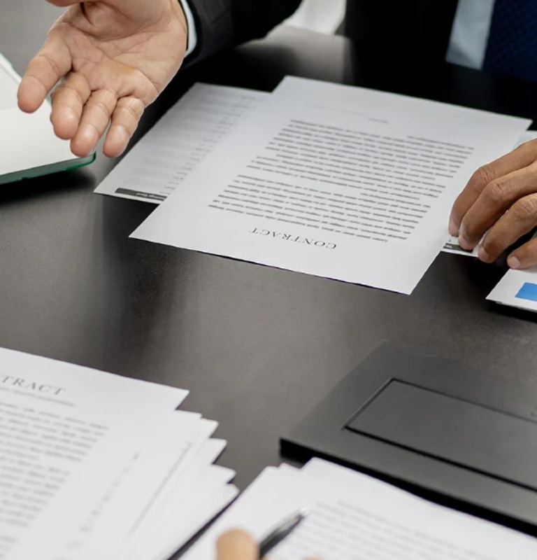Two individuals reviewing printed contract documents on a black table.