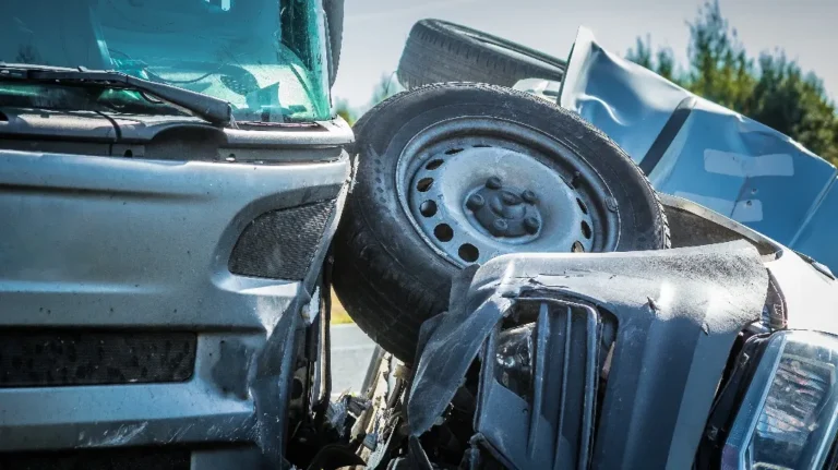 Close-up of a collision between two silver vehicles with visible damage and a detached tire.