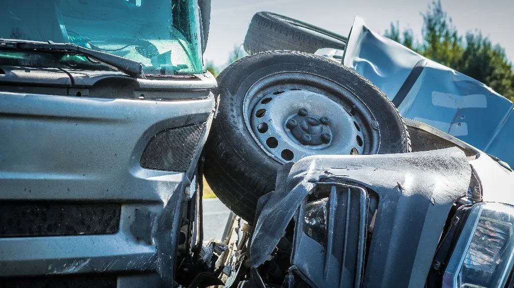 Close-up of a collision between two silver vehicles with visible damage and a detached tire.