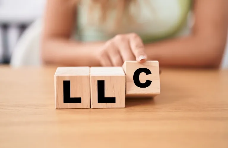 Person placing wooden block with letter "C" next to two blocks with letter "L" on wooden table.