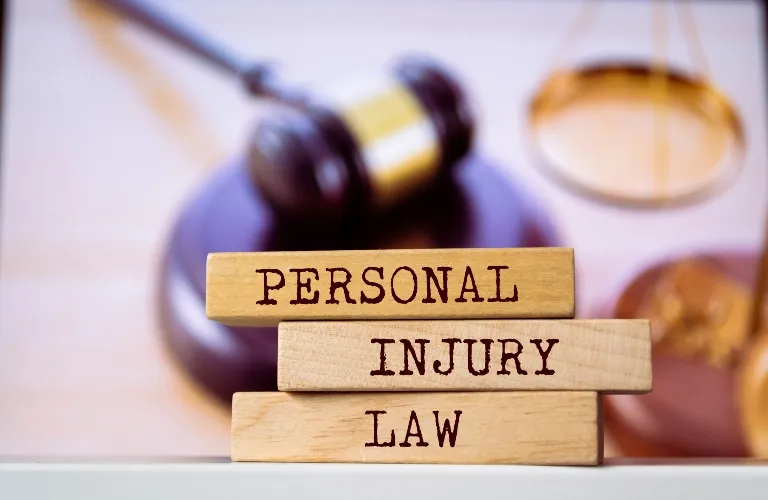 Wooden blocks with "Personal Injury Law" text, gavel and scales of justice background.